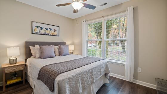 Bedroom with ceiling fan and bed with white and tan bedding