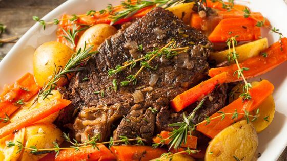 Slow cooked roast with vegetables on white platter