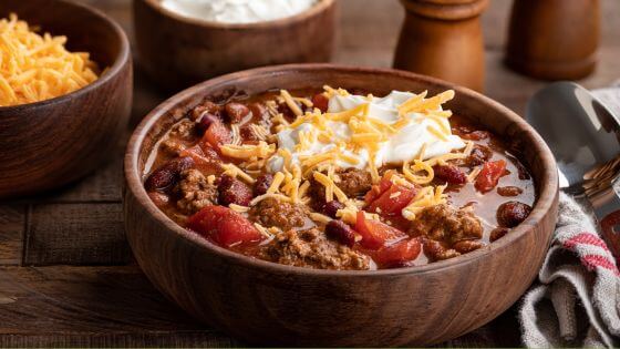 Chili with cheese and sour cream in a wooden bowl