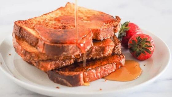 Air Fryer French toast on white plate with syrup and strawberries