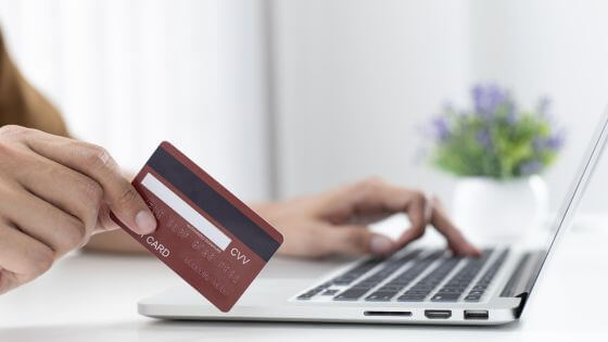 Person on laptop holding a credit card