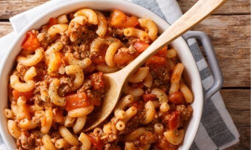 Instant Pot Goulash in white dish with wooden spoon
