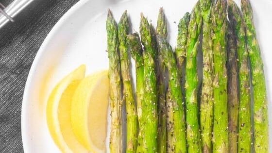 asparagus on white plate with lemon wedges