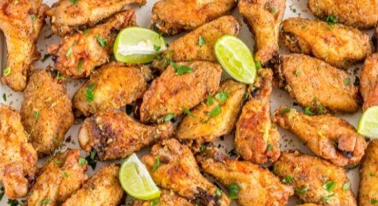 air fryer chicken wings on platter with limes
