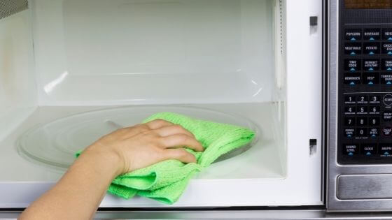 cleaning microwave with green cloth