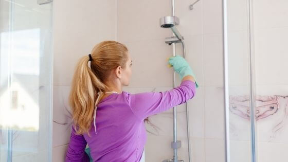 woman in purple shirt cleaning the shower