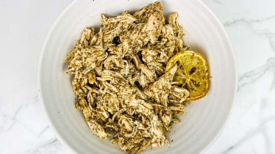 Crockpot Pesto Chicken with slice of lemon on a white plate