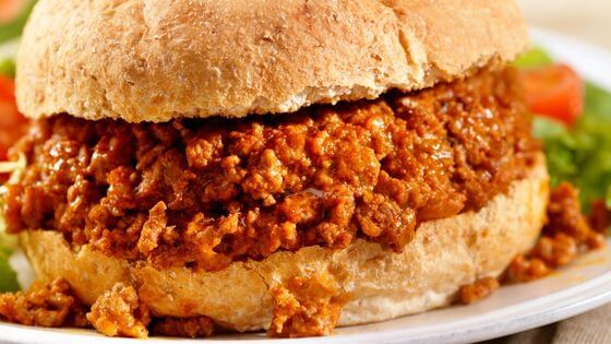 Sloppy joe on a hamburger bun on a white plate 