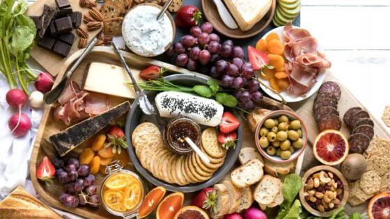 Charcuterie board with cheese, crackers, grapes, oranges, and olives