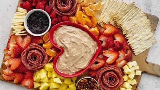 Valentines Day Charcuterie Board with heart shaped strawberries, dip and fruits and meat