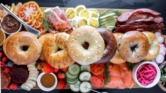 Charcuterie board with bagels, cucumbers, eggs and tomatoes