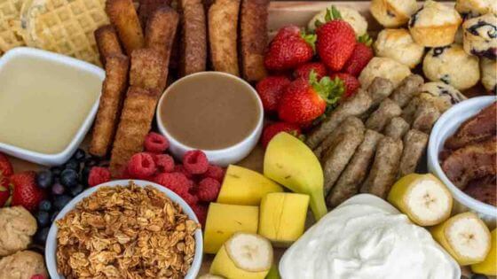 Breakfast charcuterie board with french toast sticks, strawberries, raspberries, pineapples and sausage