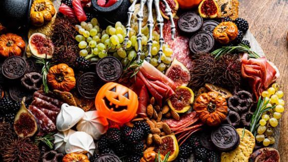 Halloween charcuterie board with mini pumpkins, grapes, and candy