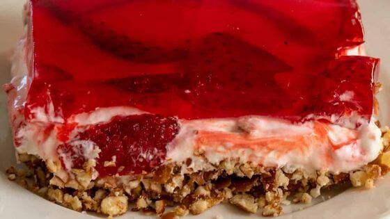 Strawberry jello salad with pretzel crust on white plate