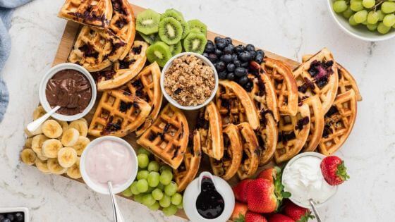 Charcuterie board with waffles, kiwi, blueberries, grapes and strawberries