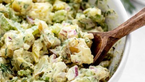 healthy potato salad recipe with no eggs in white bowl with wooden spoon