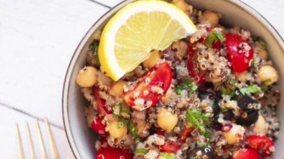 Quinoa salad for bbq with tomatoes, olives, quinoa and chickpeas in white bowl