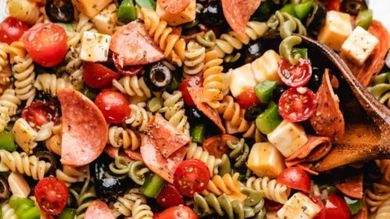 Rotini pasta with black olives, tomatoes, cheese and pepperoni in bowl