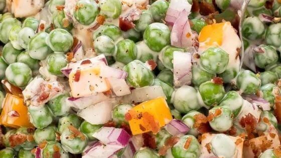 Pea salad with cheese, peas, red onions and bacon in a dish