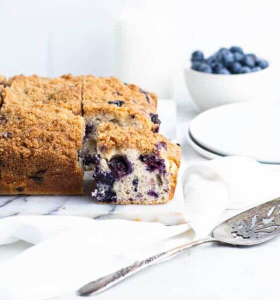 blueberry buckle with white plates and spoon next to it.