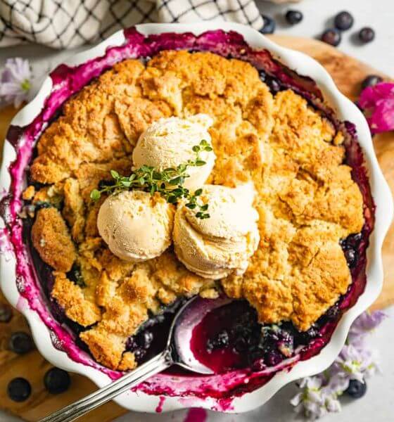 blueberry cobbler in white pie dish with vanilla ice cream on top
