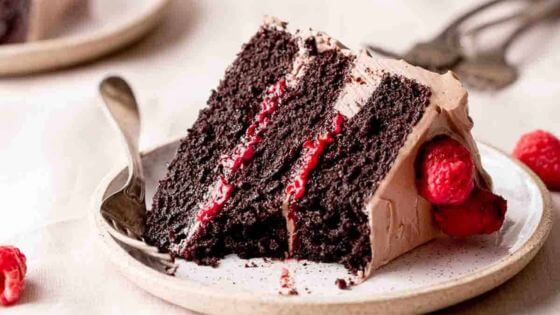 A slice of chocolate raspberry cake on a white plate with a fork