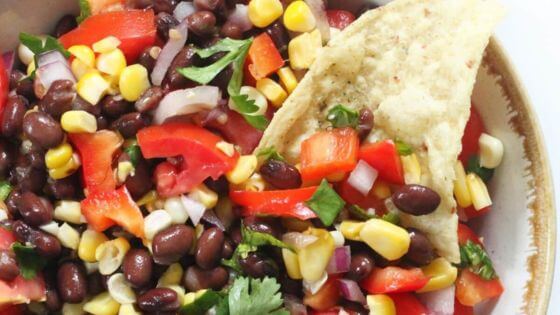 Black bean and corn salsa with tortilla chips in white bowl