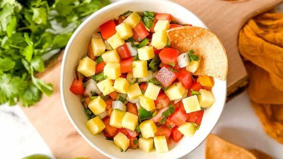 Pineapple pico de gallo in white dish on wood cutting board