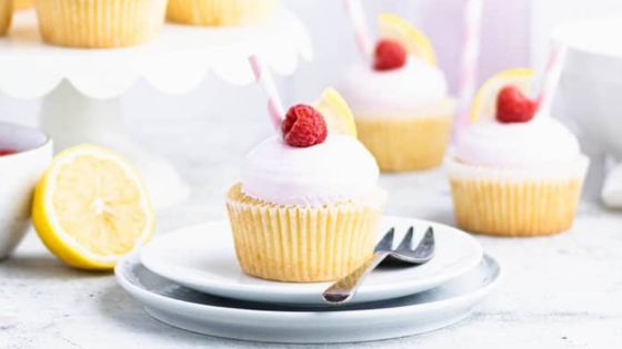 Lemon raspberry cup cakes with raspberry and lemon slices on a white plate with a fork