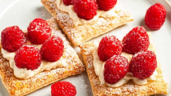 Raspberries and cream cheese on pastry sitting on a white plate