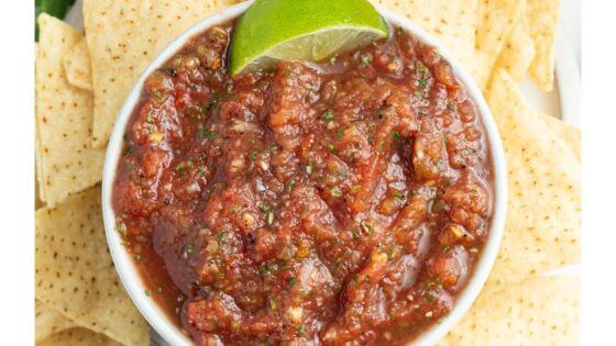 Tomato salsa with lime in white dish with tortilla chips on the side