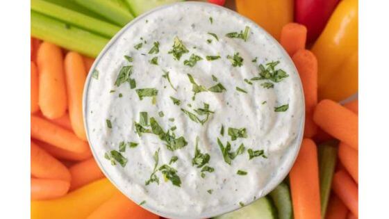 Veggie dip in bowl in the center of a vegetable platter of carrots, celery, peppers.