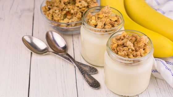Banana smoothie in mason jars with granola on top with two spoons on the side