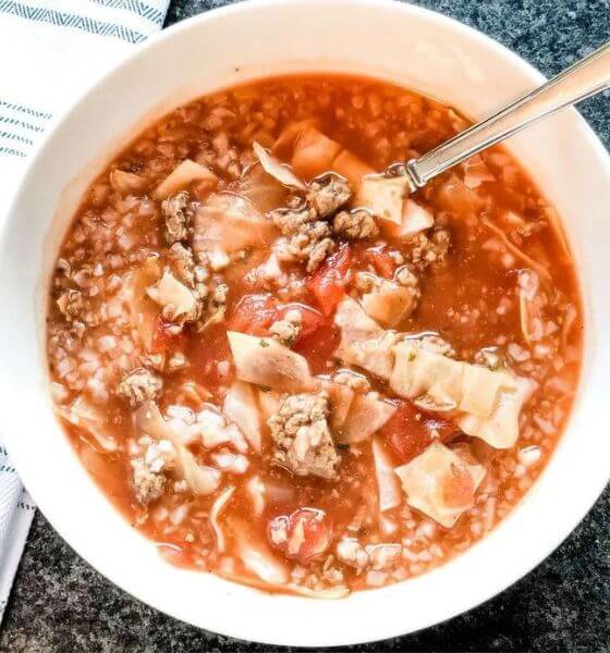 Slow cooker cabbage soup in white bowl with spoon