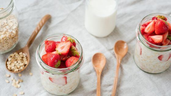 overnight oats with strawberries in mason jars with wooden spoons beside them
