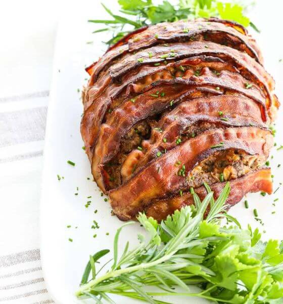 Meatloaf wrapped in bacon on white platter