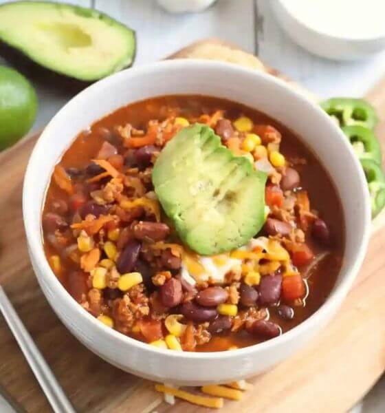 Slow cooker taco soup in white bowl with avocado on top