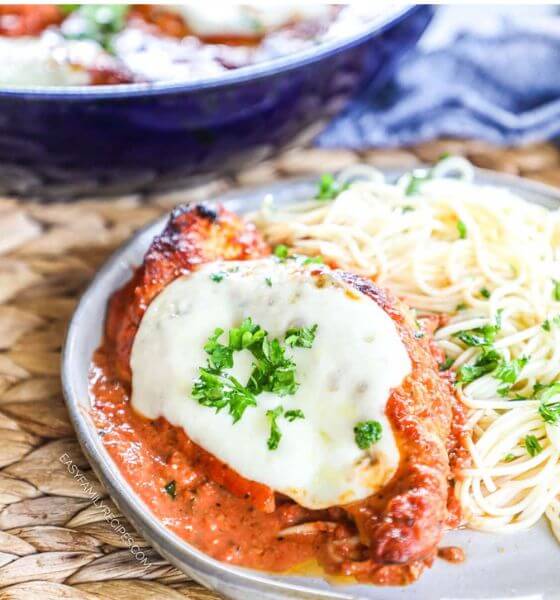 Chicken with Mozzarella on top served with spaghetti on a white plate