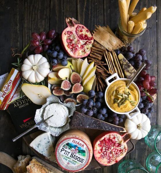 Fall cheese board with white pumpkins, cheese, blueberries, grapes, breadsticks.