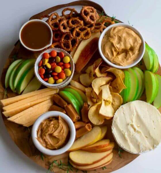 Caramel apple charcuterie board with apple slices, candy, caramel and pretzels.