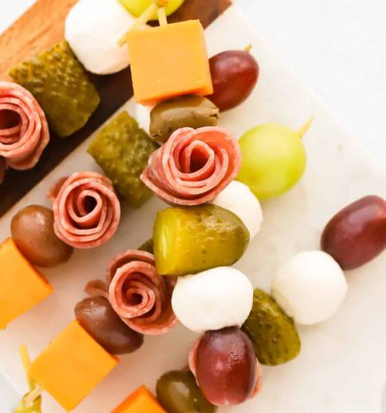 Charcuterie skewers with rose shaped salami, pickles, cheese and grapes.