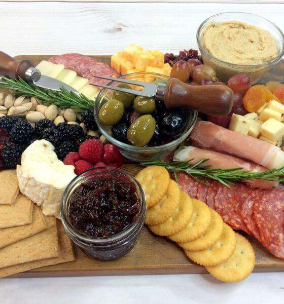 Cranberry cheese platter with crackers, olives, ham, pepperoni, cheese blackberries and raspberries.