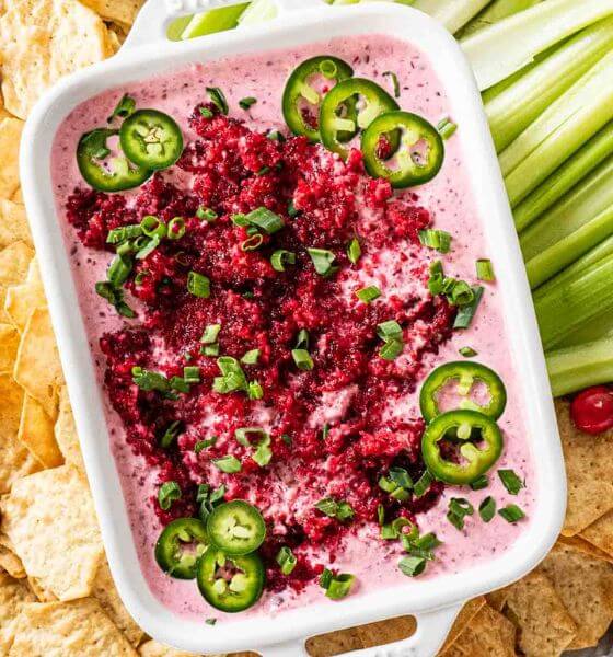 Cranberry jalapeno dip in white baking dip with celery and chips on the side.