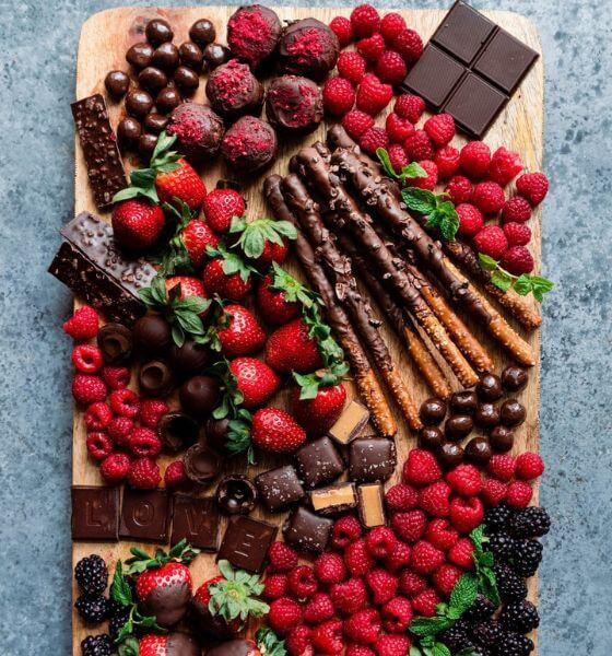 Dessert charcuterie board with strawberries, chocolate, raspberries, blackberries and pretzel rods.