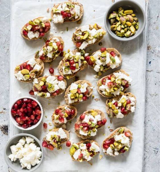 Pistachio crostini appetizer on white and grey marble background