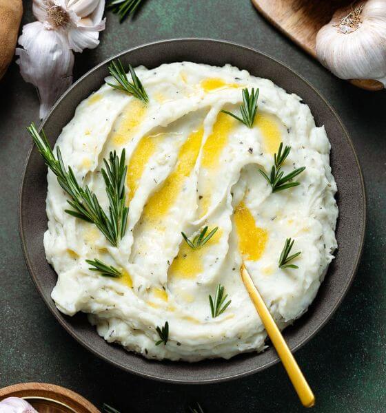 Mashed potatoes with rosemary and butter in black bowl