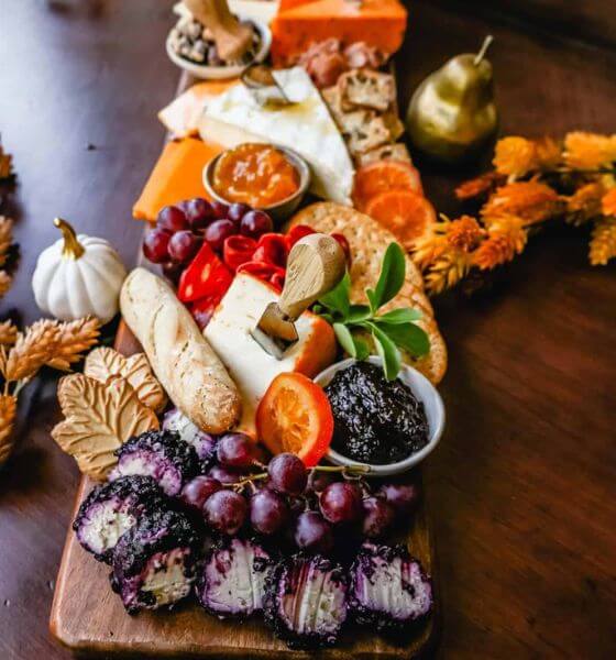 Fall charcuterie board with pumpkins, grapes, crackers, bread, cheese and spread