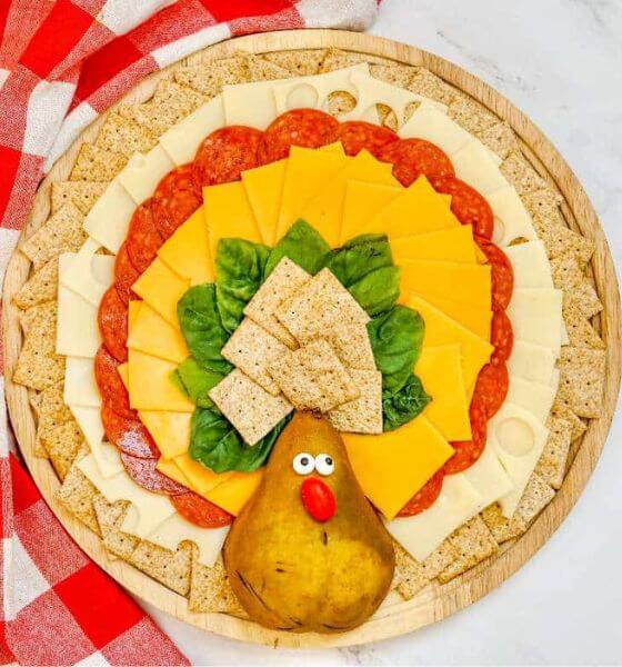 Turkey shaped charcuterie board for Thanksgiving with crackers, pepperoni and cheese