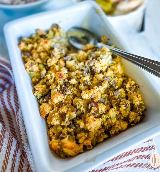 Cornbread stuffing in white baking dish with spoon