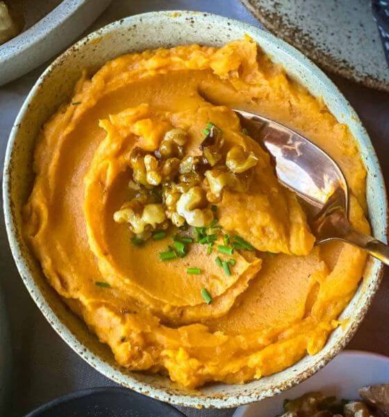 Mashed sweet potatoes in white speckled dish